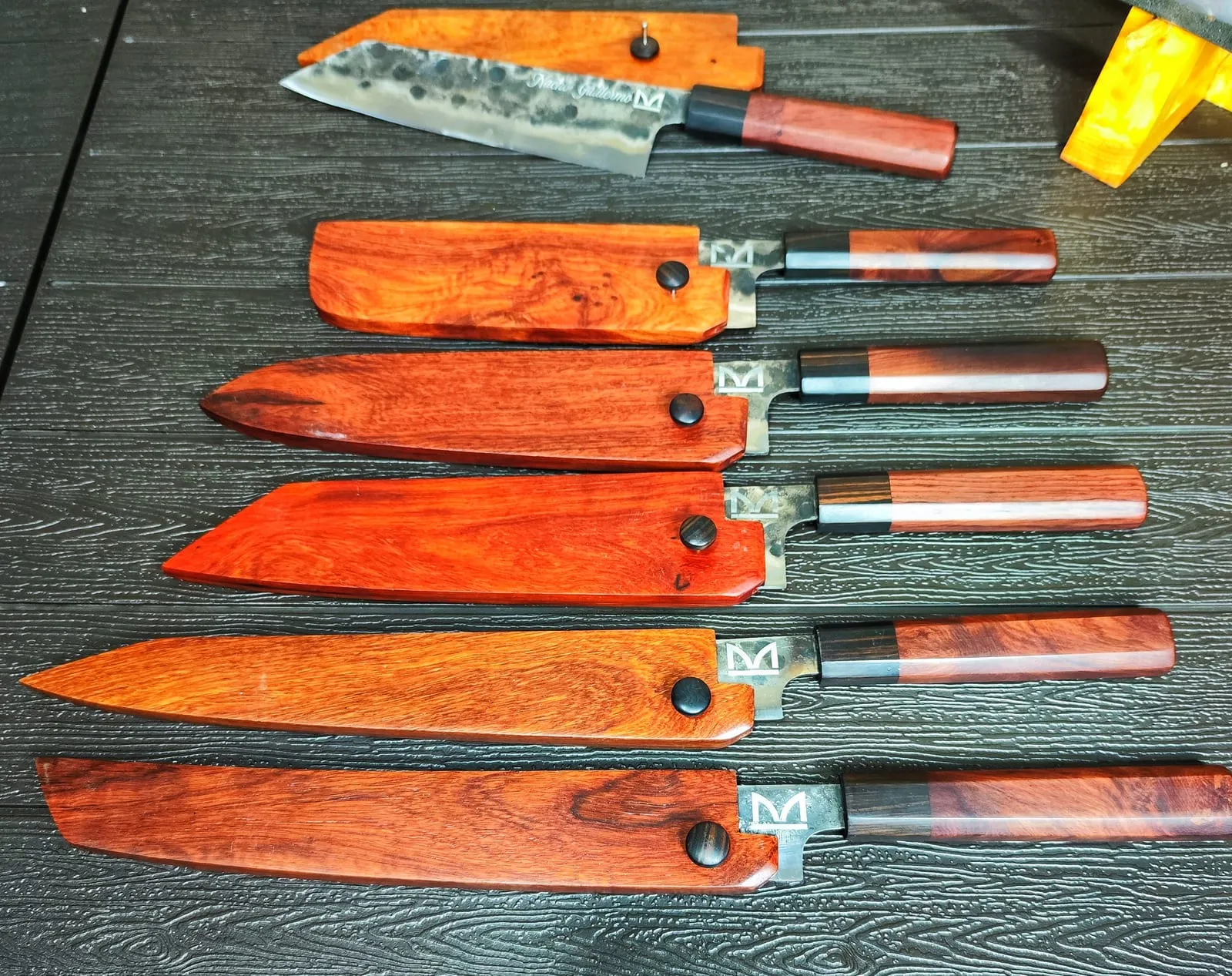 Seis cuchillos con mango y funda de madera sobre una mesa