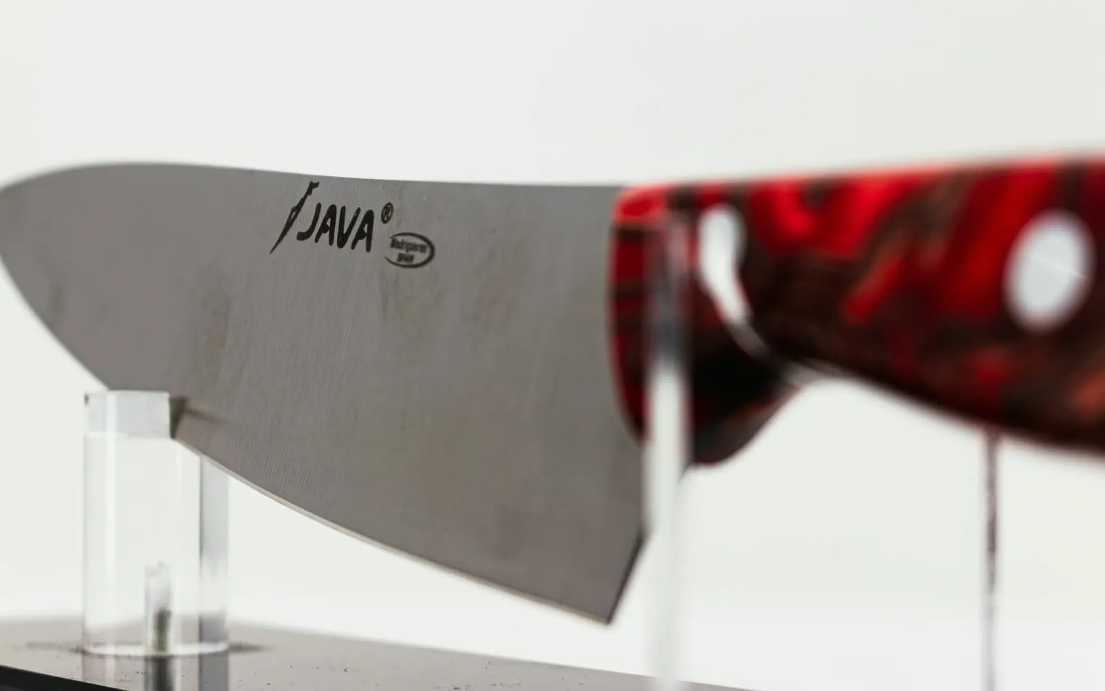 Primer plano de la marca Java grabada en la hoja de un cuchillo de mango rojo